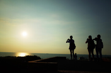 Fototapeta na wymiar 海に沈む夕日を撮る人