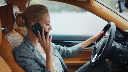 Side view of woman using phone at vehicle. Business woman sitting at luxury car