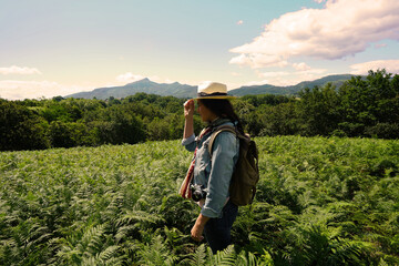 Fototapeta premium Woman with backpack on a journey in coutryside, wearing hat