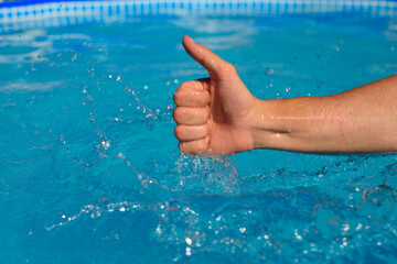 Male hand showing ok symbol on pool background