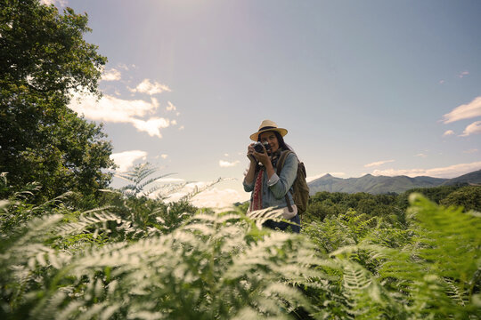 Woman with hat taking pictures in beautiful and natural landscape