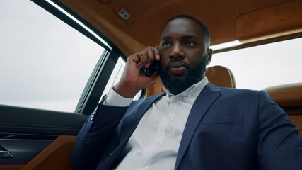 Afro business man talking mobile phone in car. African man calling phone at car.