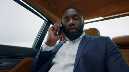 Cheerful african man calling phone at car. Afro businessman smiling at vehicle.