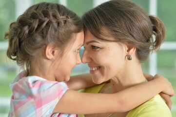Portrait of a charming little girl hugging with mom at home