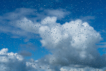 Raindrops on a window and clouds in the sky after rainy weather.