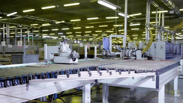 Woodworking manufacture with computerized automatic machinery. Wooden pieces of furniture moving on conveyor belt in a factory. 4K