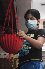 WORK IN THE SOCIAL DISTANCING ERA.
A young beautiful girl is working with plants basket wearing a mask during the corona virus era. 