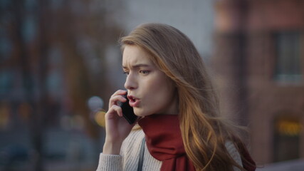 Anxious girl shouting smartphone on street. Angry woman speaking phone outdoors.