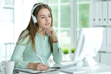 Portrait of businesswoman working in headphones in office