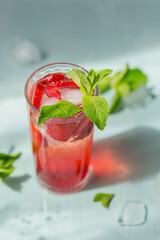 Glass of strawberry soda drink on light blue background. Summer healthy detox lemonade, cocktail or another drink background. Nonalcoholic drinks, super food, vegetarian or healthy diet concept.