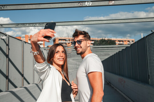 Primo piano di giovani ragazzi felici e sorridenti che si scattano un selfie con lo smartphone  mentre sono insieme in una localit&agrave; urbana di citt&agrave;