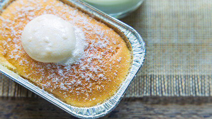High angle views close up a cup of Hokkaido milk bread with topping cream on a wooden table with a cup of milk in the morning.