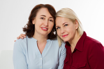 Happy menopause concept. Two healthy and beautiful middle aged women isolated on white background. Woman support woman. Closeup faces and skincare makeup.