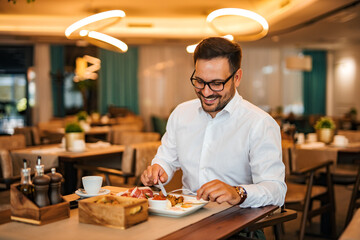 Smiling man eating breakfast in fancy restaurant, portrait.