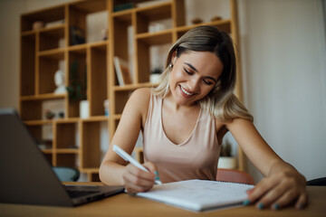 Beautiful young woman writing in paper notebook, portrait.