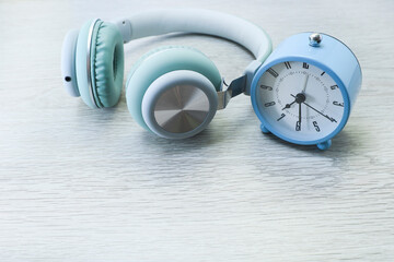 Alarm clock and headphone on the wooden table 