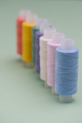 Multicolored spools of sewing thread on a gray table. The workplace of a seamstress. Sewing background with a copy of the space.