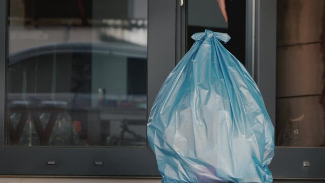 Man puts a bag of household rubbish on the doorstep of the house