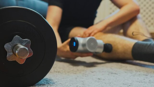 Man massaging leg with massage percussion device.