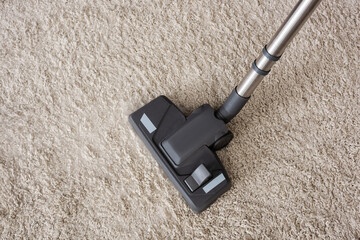 Top view of brush of vacuum cleaner on beige carpet