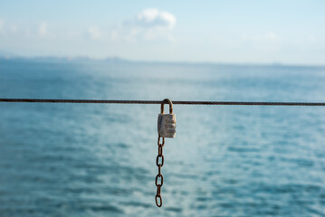 Fototapeta premium The padlock is fastened to the rope on the background of the sea
