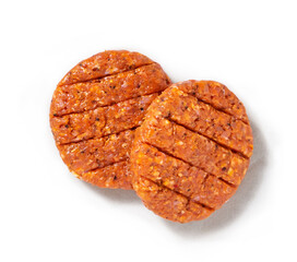 Raw hamburgers in a studio setting, on a wooden plank