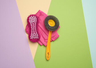 pink plastic brushes and rag for cleaning the house on a color background