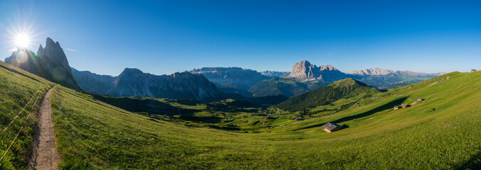 Fototapeta premium Epic mountainlandscape in Puez Odle, Dolomiti / Dolomites Alps in Italy, Seceda area, with Sass Rigais in background, small traditional cottages in green meadow and hiking trail path. Active vacation.