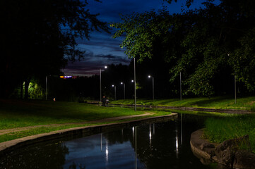 Night city park with a river and beautiful lanterns in summer