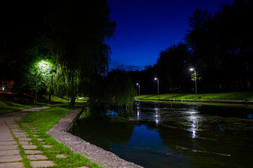 Night city park with a river and beautiful lanterns in summer
