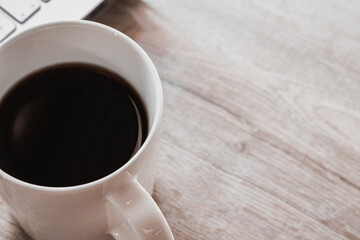 Close up black coffee in white cup and laptop on wooden table. Work from home concept
