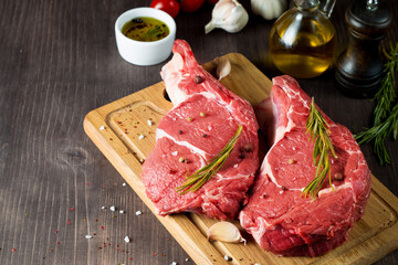Raw fresh meat, beef and pork steak, ribeye, with rosemary, pepper and salt. Marbled beef cutlet with salt and spices.
