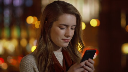 Attractive girl messaging mobile phone outdoor. Sweet lady touching phone screen