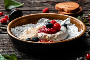Traditional French homemade baked Camembert cheese with berries and bread. European cuisine. Delicious breakfast or snack