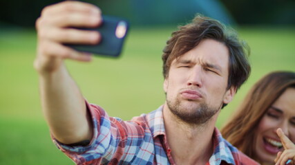 Cheerful family making funny faces on smartphone camera outdoors