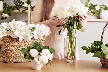 Floral background. Flower shop interior. Floral design studio, making decorations and arrangements. Flowers delivery service and sale of home plant, creating order. Peonies and roses. Florist girl