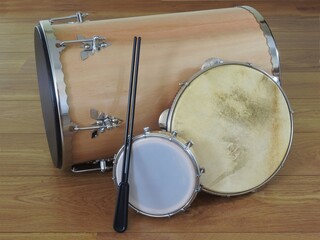 Three Brazilian percussion musical instruments: “tantan” (or “rebolo”), pandeiro (tambourine) and tamborim with drumstick on a wooden surface. They are widely used in samba and pagode ensembles.