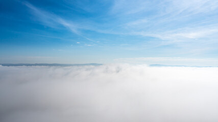 Obraz premium Blue sky above the clouds, small mountains far away