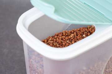 Open transparent plastic container with buckwheat.