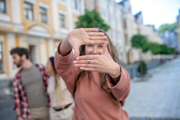 Hands of girl making an aerial lens standing on street