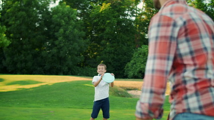 Man, boy and woman playing frisbee in park. Family throwing frisbee disc