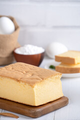 Plain classic Taiwanese traditional sponge cake (Taiwanese castella kasutera) on a wooden tray background table with ingredients, close up.