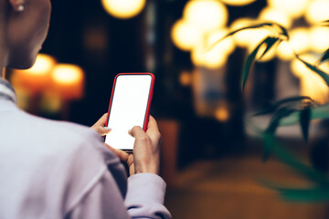 Back view of female person texting message on smartphone with copy space display for paste advertising content. Close up view woman using application on mobile phone while holding device in hands