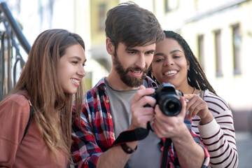 Guy and two girls looking at photos in the camera