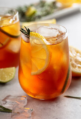 Traditional iced tea with lemon, lime and ice garnished with rosemary twigs.
