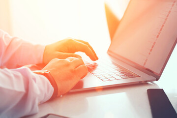 Closeup of businessman hands in blue shirt keyboarding email text message on modern pc computer at home interior table. Male work online via banking on laptop netbook. Office workspace with netbook