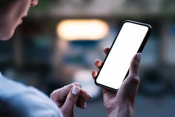 Back view from shoulder of female person looking to mock up copy space screen on mobile phone.Hipster girl using blank application on smartphone device.Close up view, texting message in social network