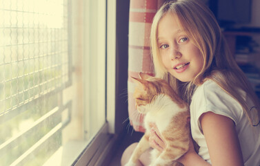 Fototapeta na wymiar Portrait of a cute 9 years old girl with lovely red cat. Smiles and happiness