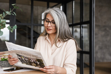 Woman indoors at home reading newspaper