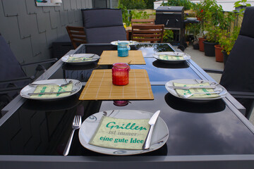 Gedeckter Glastisch mit Teller, Serviette und Besteck